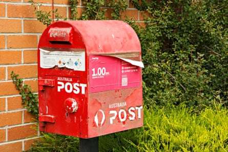 A peeling and old-looking red Australia post box.