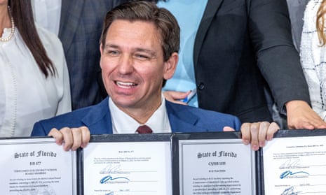 Governor Ron DeSantis show the documents after he signed legislation on teachers including banning automatic union deductions from paychecks, in Miami on 9 May.