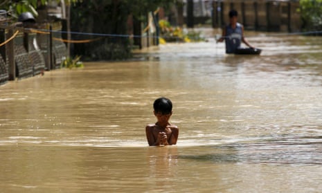 A boy wades through a flooded street in Jaen, Nueva Ecija, in northern Philippines: the death toll from Typhoon Koppu has now risen to 54.