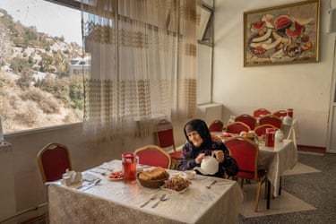 A woman pours tea from a pot in a dining room