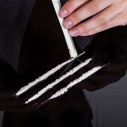 Hand holding a rolled-up banknote to snort cocaine.