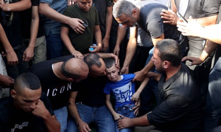 A crowd of men comfort a weeping boy