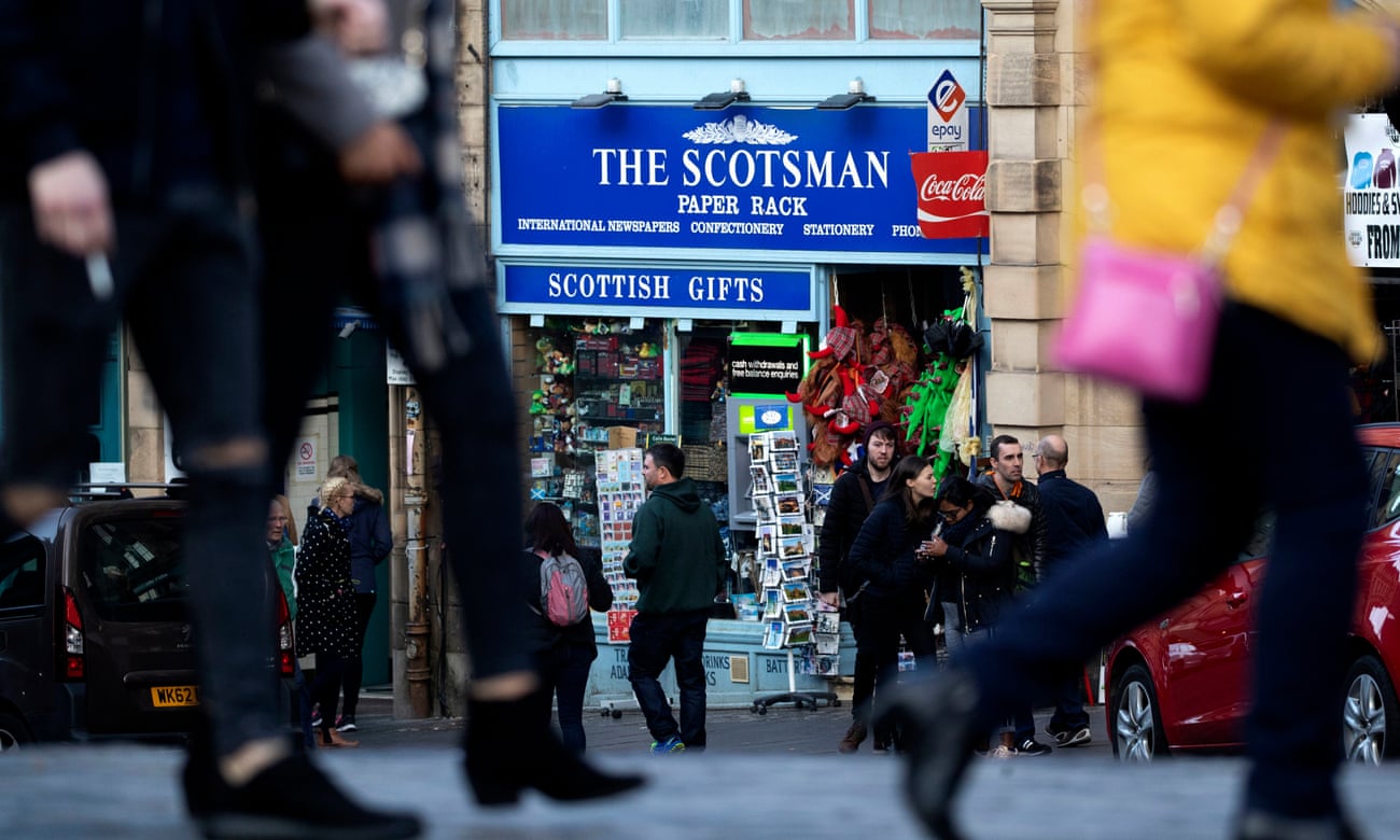 People walk past a sign for the Scotsman newspaper in Edinburgh, Scotland