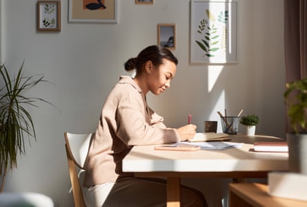 A woman writing in notebook at home with sun rays