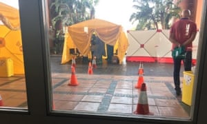 A medical tent erected outside the hotel, with a man who appears to be a doctor wearing a protective suit.