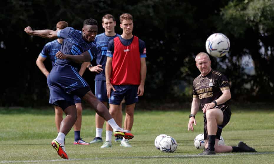 Brandon Hanlan takes aim during shooting practice, watched by the assistant manager Richard Dobson.