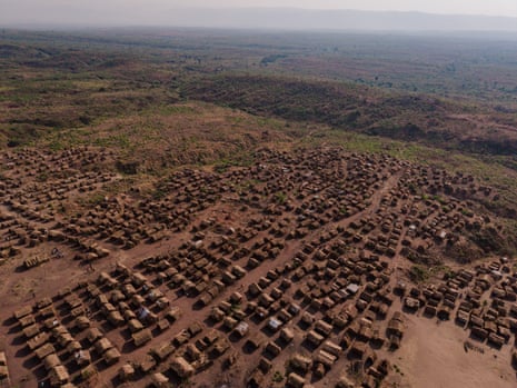 Aerial view of a large camp of makeshift huts on a plain.