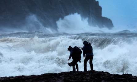 Two people silhouetted against vast, stormy seas.