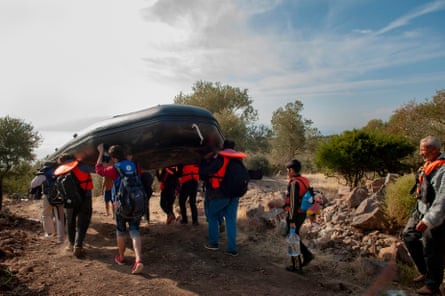 Migrants carry the inflatable boat they will travel in.