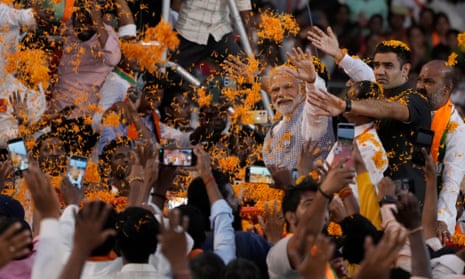 Narendra Modi is surrounded by supporters as orange streamers fall to the ground