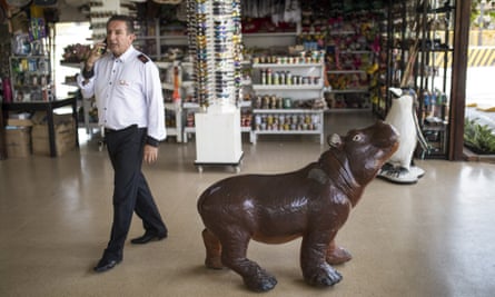A bus driver walks at a souvenir shop near Hacienda Napoles Park in Puerto Triunfo, Colombia, Tuesday, Feb. 11, 2020. Hacienda Napoles was the vast ranch owned by the late drugs baron Pablo Escobar where he built himself a zoo where he smuggled in elephants, giraffes and other exotic animals, among them four hippos that have now reproduced and their many off-spring are now endangering native animals while also leaving farmers and fisherman fearing for their safety. (AP Photo/Ivan Valencia)