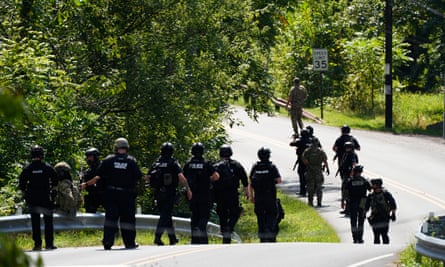 lots of police in black walking on a rural road