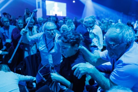 A man raises a walking stick as a protester is surrounded by Reform supporters.
