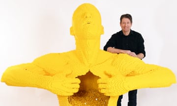 Nathan Sawaya with his sculpture Big Yellow, a man made of yellow Lego opening his chest with his hands