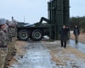 Kim Jong-un walking along a track with a large missile launcher behind him and soldiers standing to attention