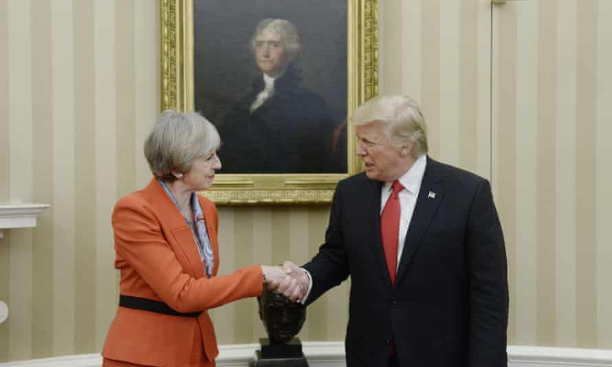 May and Trump hold hands in front of a portrait