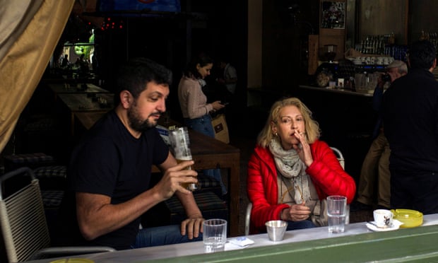 A woman smokes in an Athens bar. Few measures have been as controversial as official efforts to wean Greeks off nicotine.