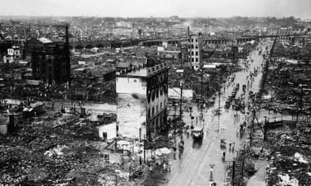 A black and white aerial view of collapsed buildings beside a main road in Tokyo.