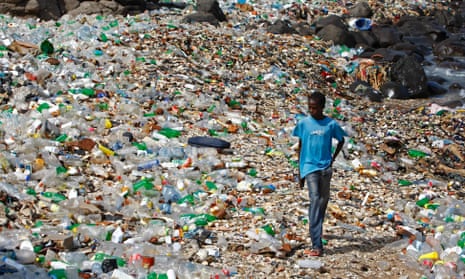 A boy walks along a polluted beach strewn with predominantly plastic bottles in the village of Ngor, Dakar, Senegal
