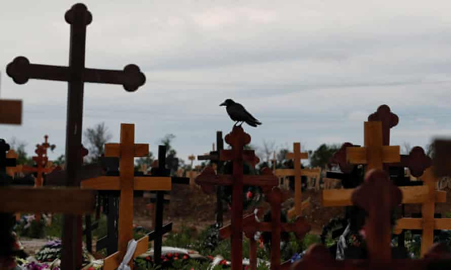 A bird sits on a cross amid newly-made graves at a cemetery in the course of Ukraine-Russia conflict in the settlement of Staryi Krym outside Mariupol, Ukraine May 22, 2022.