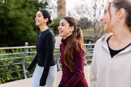 Three young women smiling and walking in the city