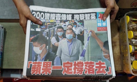 A vendor arranges fresh copies of the Apple Daily newspaper in Hong Kong showing a front page photo of its founder Jimmy Lai being escorted through the paper’s newsroom by police following his arrest under the new national security law