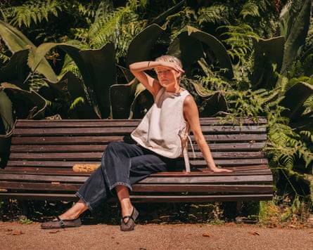 Alex Holder sitting on a bench with lush trees behind her