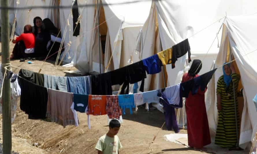Syrian refugees walk along their tents at a refugee camp in the Turkish border town of Yayladaği