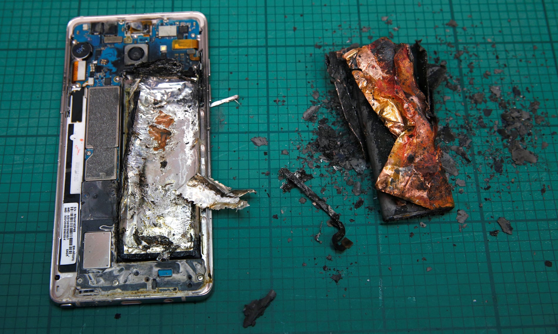 A Samsung Note 7 handset is pictured next to its burnt battery after catching firy during a test in a laboratory.