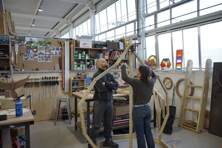 Two people working on a wooden structure inside the warehouse