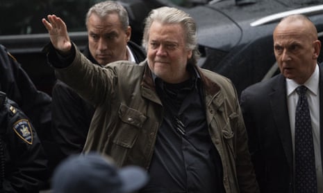 Steve Bannon, wearing a jacket, waves to a crowd.