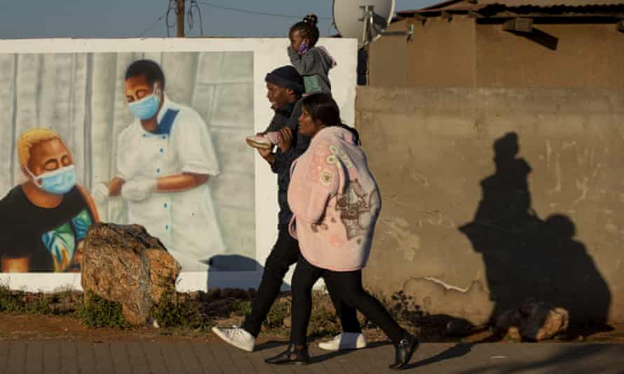 A family walks past a mural promoting vaccination for Covid-19 in Duduza township, east of Johannesburg, South Africa