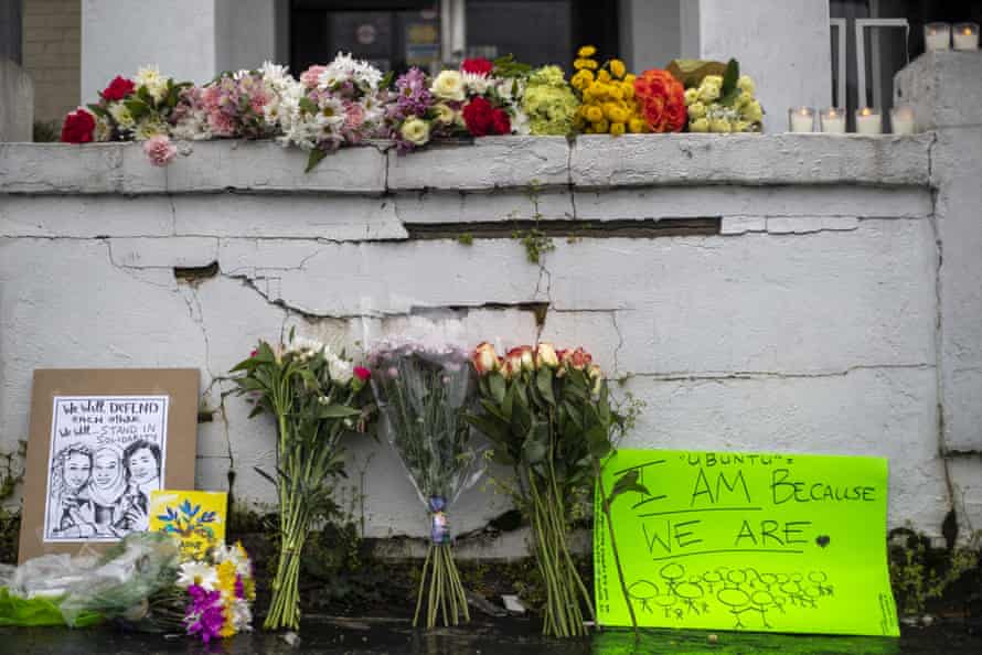 Flowers and signs are displayed at a makeshift memorial outside of the Gold Spa.