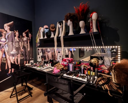 Mockup of a backstage area with a mirror, scattered makeup and wigs on mannequin heads