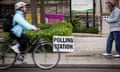A cyclist rides past a polling station in London