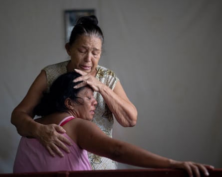 Yaritza García is comforted by her mother, Carmen Sivira, in front of the altar for her daughter funeral’s in their home