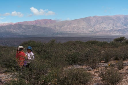 Dos mujeres en primer plano, con el paisaje montañoso rico en recursos de Jujuy, en el noroeste de Argentina, como telón de fondo.