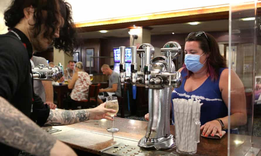 A staff member serves a woman at the bar at Wetherspoons pub The Moon Under Water in Manchester, England