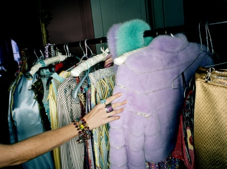 A woman selecting from a rack of second hand and vintage clothes in a home.