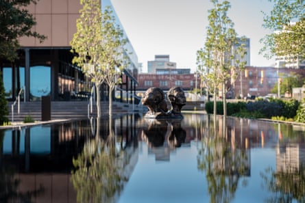statue of two heads above a pool of water outside of museum