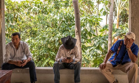 Salomón Bámaca (left) sit alongside two other men on a small wall at a house in San Miguel Ixtahuacán