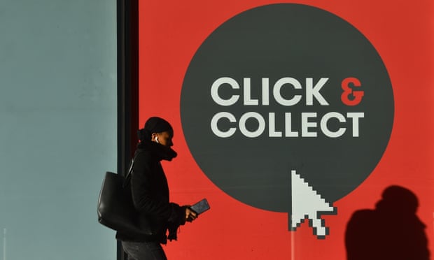 A woman walks past a click-and-collect sign in Birmingham