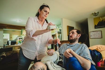 A woman pours a liquid into a feeding tube attached to her son