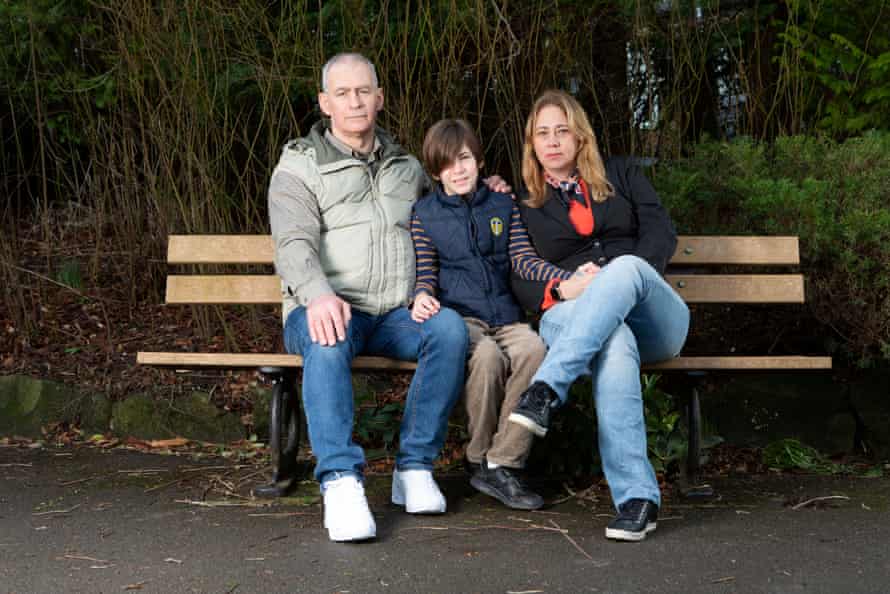 Um casal senta-se com seu filho em um banco de parque