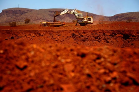 Red earth in the foreground with an excavator at the back, in front of mounds of red earth