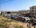 Yemenis queue beside a long line of vehicles to refill gas bottles