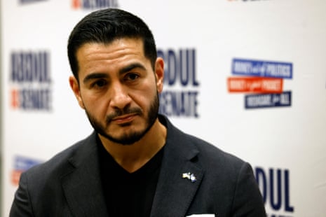Abdul El-Sayed, senatorial candidate, looks ahead with a serious expression in front of a blurred banner