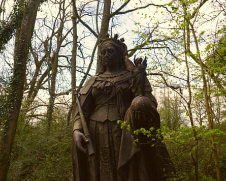 A dark-brown statue of Victoria amid greenery