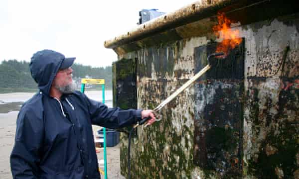 A volunteer burns marine organisms from a Japanese dock on Agate Beach, Newport, Oregon