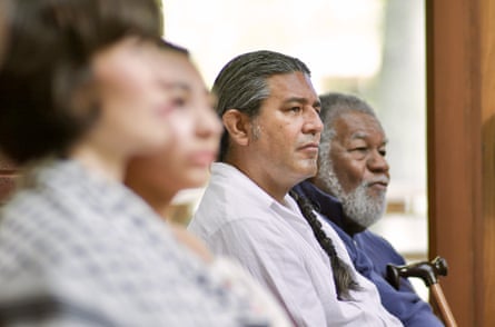 four people - two blurry in foreground, then Keme and Black in background - seated in a row